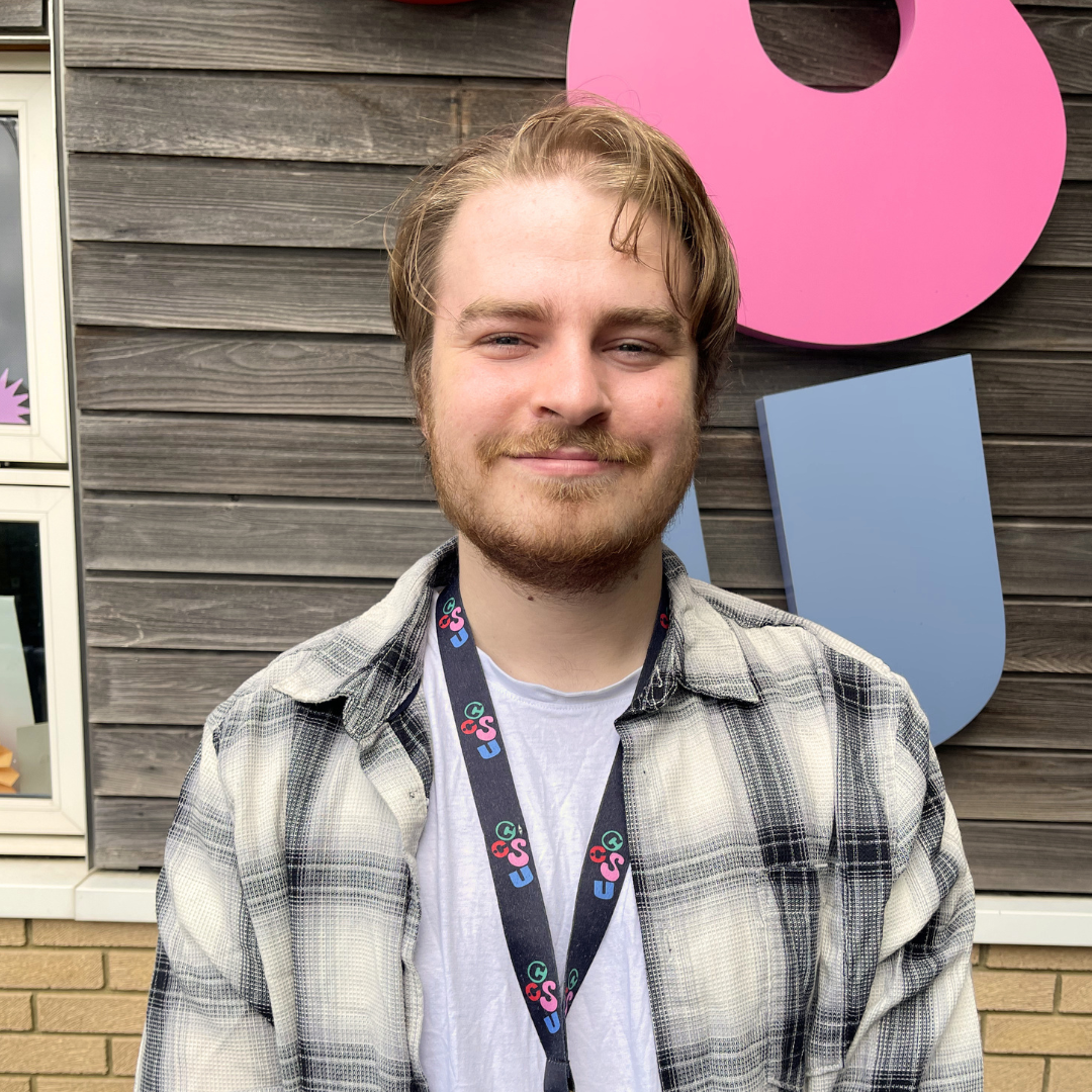 White person with short wavy light brown hair and beard smiling at the camera