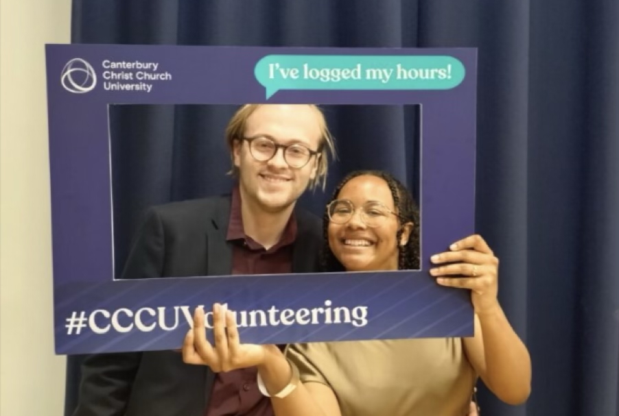Two people wearing glasses and smart clothes holding up a frame that says 'I've logged my hours!' 