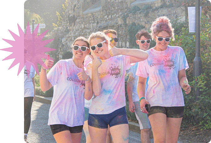 Group of three girls wearing white tshirts emblazened with 'Colour Run', the t-shirts have been splashed with different colour paints.